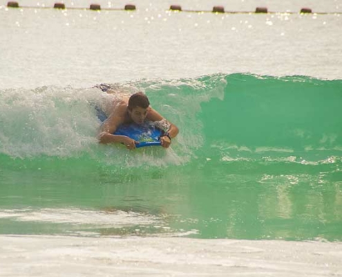 Anse Lazio, image shows a sufer in the water riding a wave